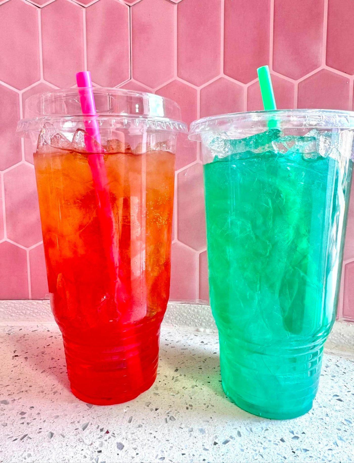 Two energy drinks side by side, one orange-red the other bright teal