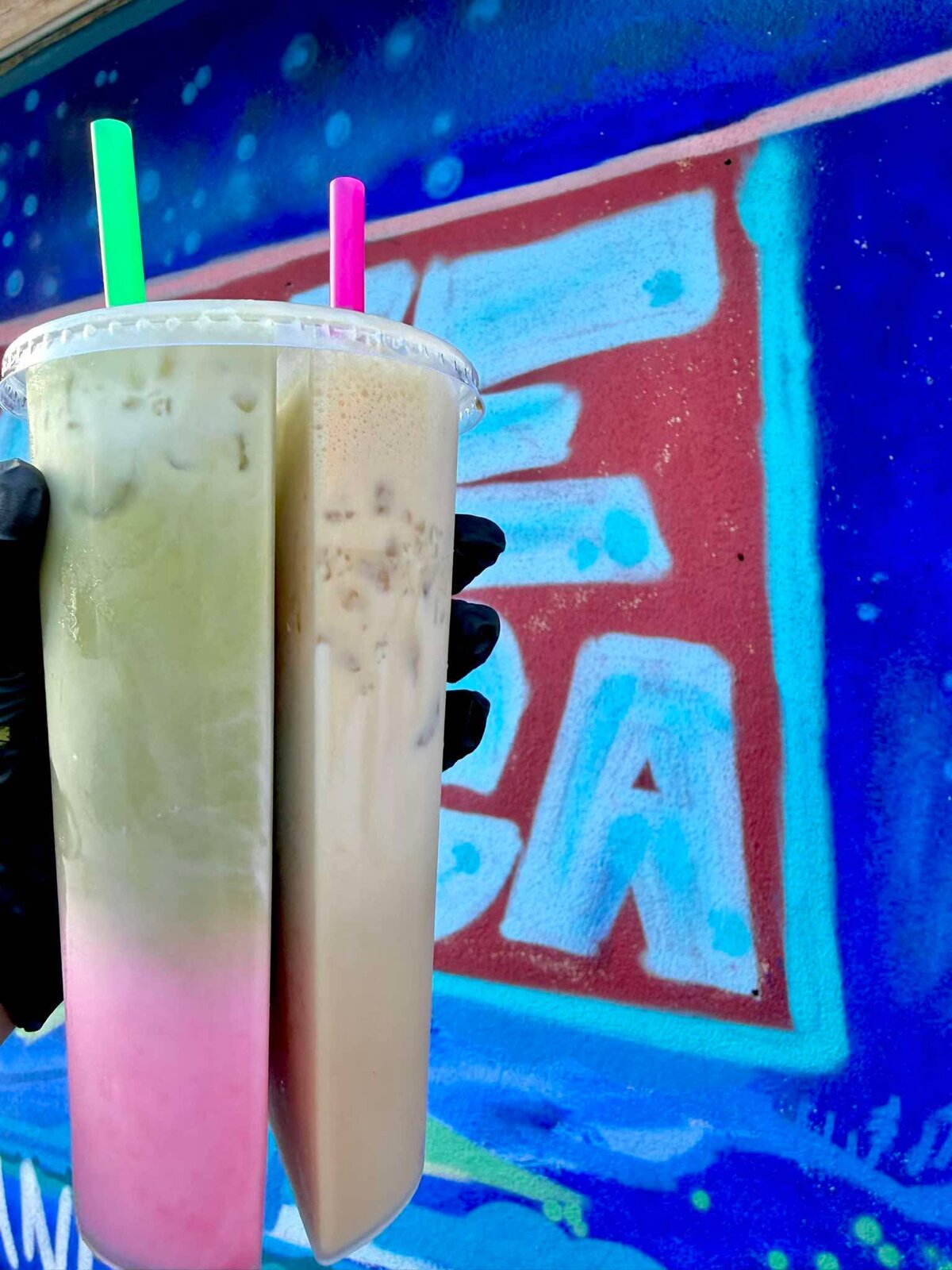 Two iced green tea drinks side by side against a colorful mural