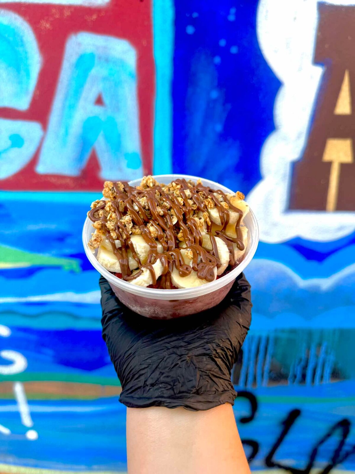 A&ccedil;a&iacute; bowl topped with banana slices, granola, and chocolate drizzle